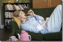 A young woman lying on her couch eating chocolate